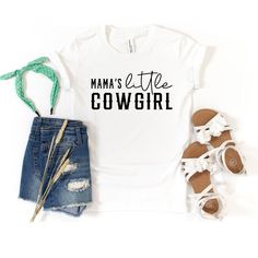 Looking for a cute tee for your kids? We have the perfect Mama's Little Cowgirl graphic tee addition to their closet! Cute Cotton T-shirt With Name Print, Cute White T-shirt With Letter Print, Family Matching Letter Print T-shirt For Spring, Cute Graphic Print T-shirt For Mother's Day, Cute Mother's Day Graphic Print T-shirt, Cute Mother's Day T-shirt With Graphic Print, Spring Fun T-shirt With Name Print, Cute Spring T-shirt With Funny Text, Cute Mother's Day T-shirt With Funny Text