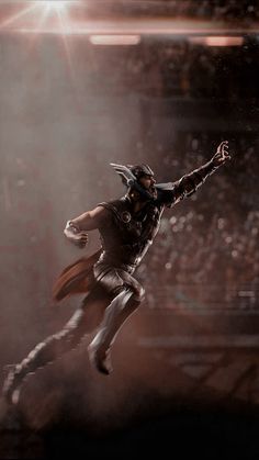 a man dressed as thor is flying through the air in front of an arena full of people