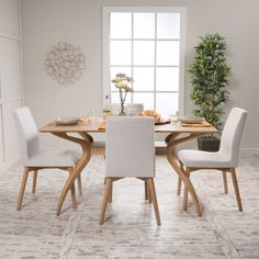 a dining room table with four chairs and a potted plant in the corner next to it