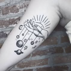 a person with a tattoo on their arm holding the sun and planets in front of them