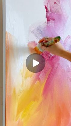 someone is painting a large piece of art with pink and yellow paint on the wall