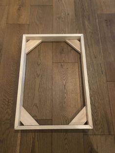 an empty wooden frame sitting on top of a hard wood floor