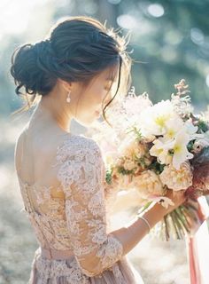 a woman holding a bouquet of flowers in her hand and looking down at the ground