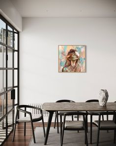 a dining room table with chairs and a painting on the wall above it that has a woman's face