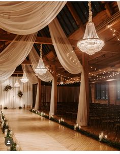 an indoor wedding venue with white drapes and chandeliers