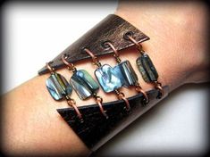 a woman's arm wearing a bracelet with glass beads and copper wire wrapped around it