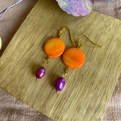 Orange Purple is a pair of handmade pearl earrings. The name speaks for itself with the two colors used: orange and pink/purple. These earrings give every outfit a pop of color and complete every outfit. The pendant made of various materials hangs from the gold-colored metal ear hook. The top one, the flat circle, is made of orange painted mother-of-pearl/shell. Below hangs a pink / purple freshwater pearl. Because the earrings are made with beads that I had in my collection for 10 years, I can't get here again. So you know for sure that you have an (almost) unique pair! There will be several color combinations of this model earring. Because these earrings are made with natural materials, each earring is different. The patterns in the shell, the shapes of the pearls, etc. are different per Vibrant Orange Drop Earrings, Purple Pearl Earrings Gift, Purple Pearl Earrings As Gift, Purple Pearl Earrings For Gift, Purple Pearl Earrings For Pierced Ears As A Gift, Handmade Multicolor Pearl Drop Earrings, Purple Round Pearl Earrings For Gift, Handmade Purple Dangle Pearl Earrings, Purple Dangle Pearl Earrings As Gift