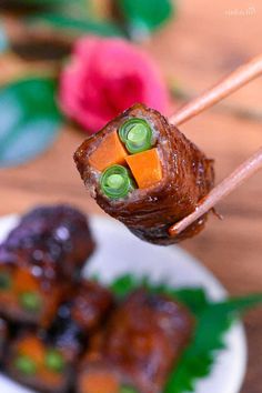 chopsticks holding up food on a plate with flowers in the backgroud