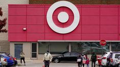 people walking in front of a target store with cars parked outside and on the street