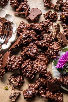 there are many pieces of chocolate and flowers on the table with spoons next to them