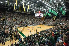 a basketball game is being played in an indoor arena with people watching from the stands