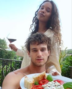 a man holding a plate with food on it and a woman standing next to him