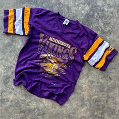 minnesota viking shirt laying on the ground with it's sleeves rolled back and two stripes down