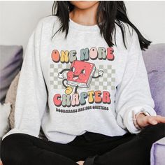 a woman sitting on a couch wearing a sweatshirt that says one more computer