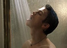 a shirtless man standing in the shower with his head up and eyes closed, looking upward