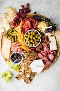 an assortment of cheeses, meats and crackers on a platter