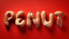 the word peanut spelled with peanuts on a red background