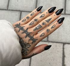 a woman's hand with black nail polish and tattoos on it