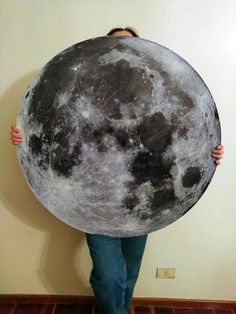 a person holding up a giant moon pillow