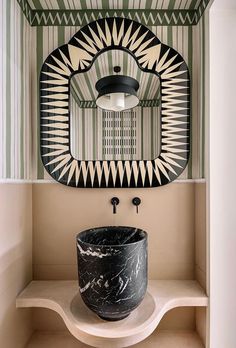 a black and white sink sitting under a mirror in a bathroom next to a shelf