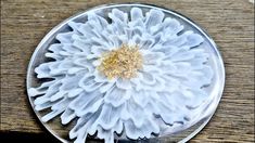 a white and gold flower sitting on top of a glass plate