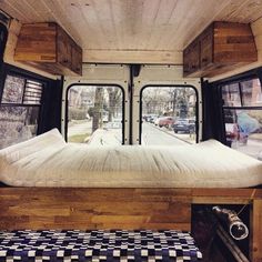 a bed in the back of a camper van with windows looking out onto a street