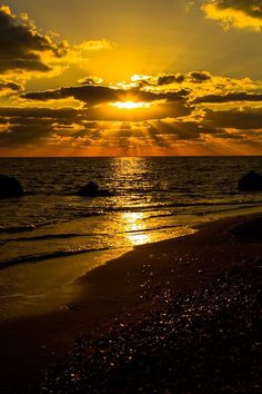 the sun is setting over the ocean with clouds