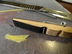 a pair of scissors on top of a wooden table next to a piece of wood