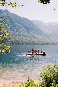 several people are on a boat in the water with mountains in the backgroud