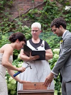 a man and woman are exchanging vows in front of an older gentleman holding a hammer