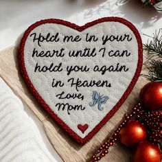 a heart shaped embroidered on top of a cutting board next to christmas ornaments and decorations