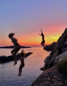 people jumping off rocks into the water at sunset