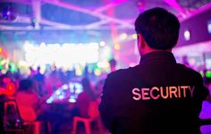 security officer standing in front of an audience at a party or event with bright lights