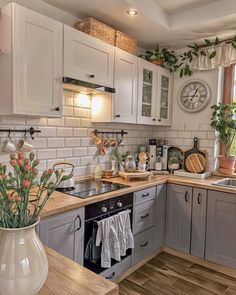 a kitchen filled with lots of wooden counter tops and white cabinets next to a window