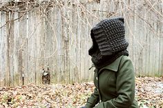 a person wearing a black knitted hat and holding a tennis racquet in front of a wooden fence