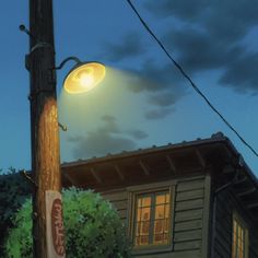 a street light sitting on the side of a wooden pole next to a tree and building