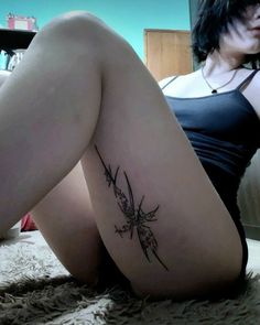 a woman laying on the floor with her legs crossed and tattoos on her thighs,