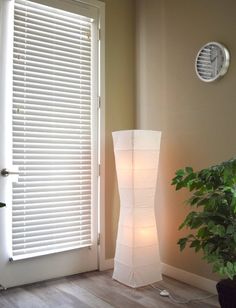 a lamp that is sitting next to a door with blinds on the window sill