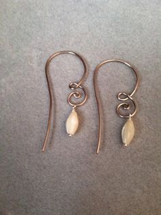 two pairs of earrings sitting on top of a gray table next to a pair of scissors