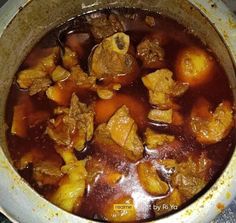 a pot filled with meat and potatoes on top of a stove