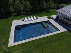 an aerial view of a swimming pool with lounge chairs on the lawn next to it