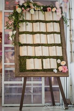 an old book with moss and flowers on it is displayed in front of a window