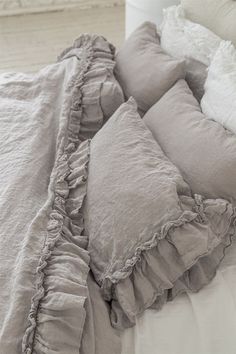 an unmade bed with ruffles and pillows