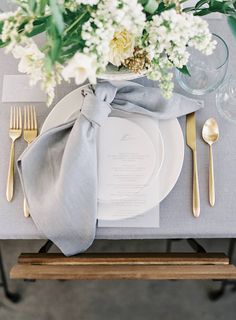 a table setting with silverware and white flowers