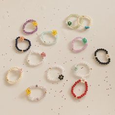 several different colored bracelets are arranged on a white surface with confetti sprinkles