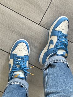 a person wearing blue and white sneakers standing on a wooden floor