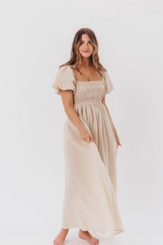 Be the life of the party in the Nan Maxi Dress! This beautiful gown comes in a gorgeous, multi-season neutral hue, and features a smocked bodice and puffed sleeves that can be worn on or off the shoulder - it's like getting two dresses in one! Style the Nan with slides for a casual, feminine outfit, or with neutral heels for the perfect event dress. FIT: Runs true to size. MATERIAL: GARMENT DETAILS: Neutral maxi dress with empire waist silhouette, smocked bodice, and puffed sleeves with elastica Chic Maxi Length Puff Sleeve Dress With Smocked Back, Chic Maxi Puff Sleeve Dress With Smocked Back, Puff Sleeve Midi Dress For Garden Party, Puff Sleeve Dress With Smocked Back For Garden Party, Garden Party Puff Sleeve Dress With Smocked Back, Flowy Smocked Bodice Puff Sleeve Dresses, Spring Puff Sleeve Dress For Gatherings, Elegant Dress With Smocked Back And Bishop Sleeves, Flowy Ruched Puff Sleeve Dress For Garden Party