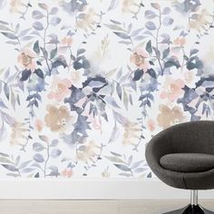 a chair sitting in front of a wall with flowers painted on the wall behind it