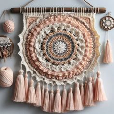 a crocheted wall hanging with tassels and other items on it,