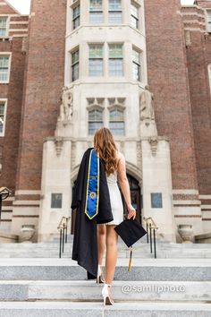 a woman is walking up the steps in front of a building with a graduation robe on